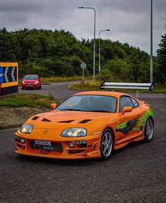 an orange sports car is parked on the street