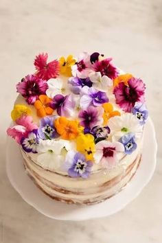 a cake with white frosting and multicolored flowers sitting on top of it