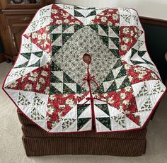 a quilted table topper on a wicker chair with red and green flowers