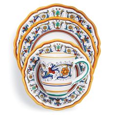 a set of four plates with colorful designs on the front and sides, each holding a cup