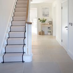 there is a staircase leading up to the first floor in this house with beige carpet and white walls