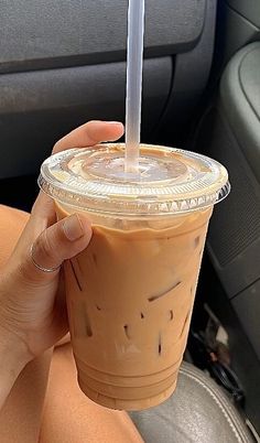 a woman holding a drink in her hand while sitting in the back seat of a car