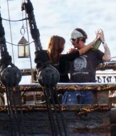 a man and woman standing on top of a boat