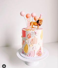 there is a cake decorated with animals and balloons on the top of it, as well as decorations