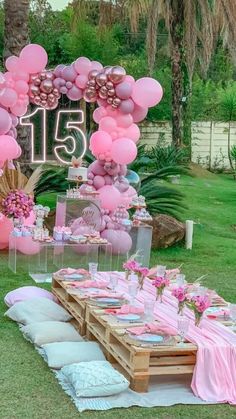 a table set up with pink balloons and decorations for a 21st birthday party in the garden