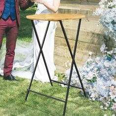 a man and woman standing next to each other in front of a wooden wall with flowers