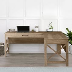 a wooden desk with a laptop and potted plants on it in front of a white wall