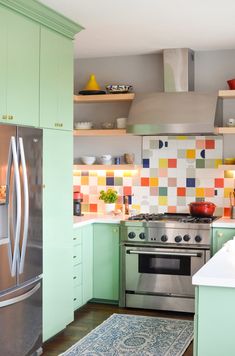 a kitchen with green cabinets and stainless steel appliances, including a stove top oven in the center