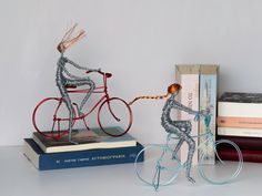 two books are stacked on top of each other and one figurine is riding a bike