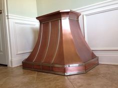 a copper colored stove hood sitting on the floor