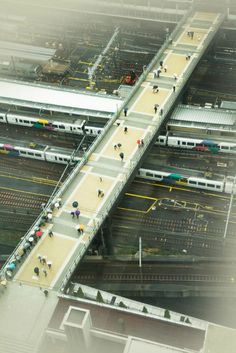 an aerial view of people walking on a bridge over train tracks in the middle of a city