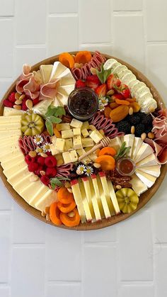 a platter filled with cheeses, meats and vegetables on a white table