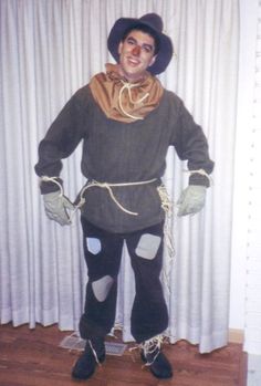 a man dressed up as a scarecrow in front of a curtain with chains attached to his legs