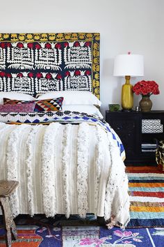 a bed with an intricate headboard and colorful rugs on the floor next to it