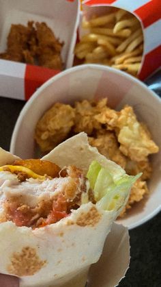 a person holding up a burrito in front of some other food items on a table