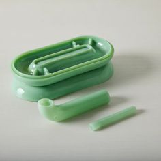 a green plastic container with three toothbrushes in it and two other items next to it