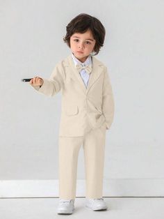 a young boy in a suit and tie holding a remote control