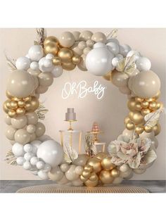 a white and gold baby shower with balloons on the wall, cake table and decorations