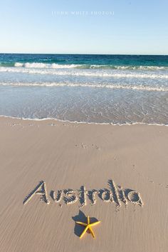 the word australia written in the sand with a starfish on it's side