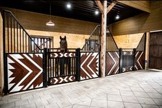 a dog standing on top of a wooden gate next to a brick floor in an enclosed area