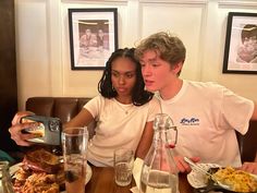 two people sitting at a table with plates of food and drinks in front of them