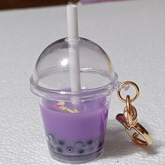 a purple candle with a keychain attached to it sitting on a white surface