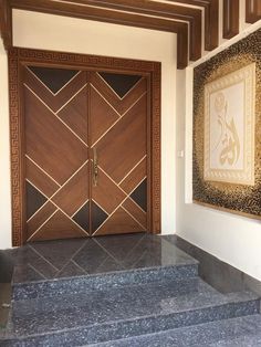 an entry way with stairs leading up to two doors and a painting on the wall