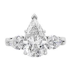 an engagement ring with three pear shaped diamonds on the sides and four clawed shoulders