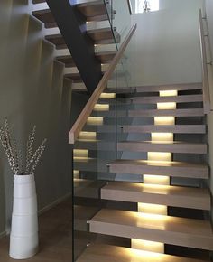 a stair case with lights on the side and some flowers in a vase next to it