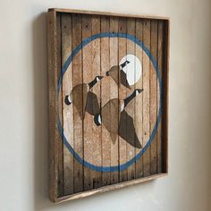 a wooden sign with two birds on it's side hanging on the wall next to a white wall