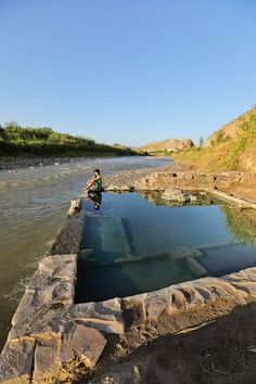 a man sitting on the edge of a body of water