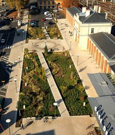 an aerial view of a city square with many trees and bushes in the center, surrounded by buildings