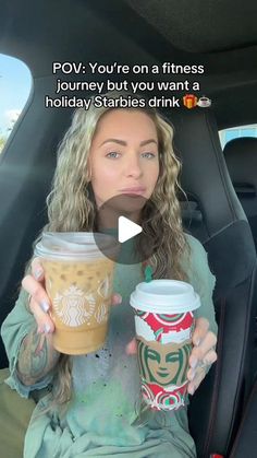 a woman sitting in the back seat of a car holding two cups