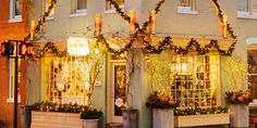 the front of a building decorated with christmas lights and potted plants in front of it