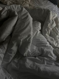 an unmade bed with white sheets and pillows