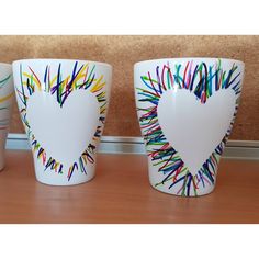 three white cups with colored sprinkles in the shape of a heart on them