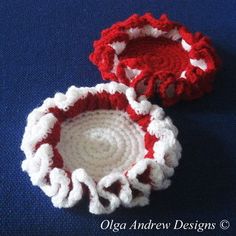 two red and white crocheted dishes on a blue surface