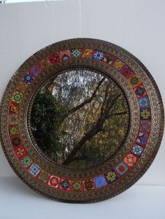 a circular mirror is hanging on the wall with trees reflected in it's reflection