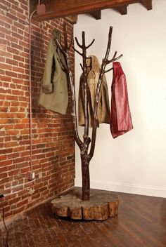 a tree with clothes hanging on it in front of a brick wall and wooden floor