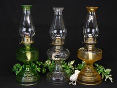 three glass vases sitting next to each other on top of a black tablecloth