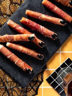 several pieces of meat wrapped in bacon sitting on a black cutting board next to a glass of wine