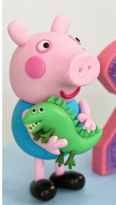 a peppa pig holding a green alligator toy