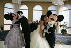 the bride and groom are kissing in front of mickey mouse at their wedding reception,