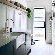 a kitchen with white walls and wooden flooring next to an open door that leads to the outside