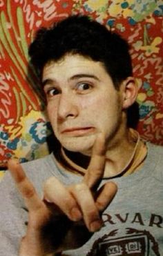 a young man making the v sign with his fingers while sitting in front of a colorful wall