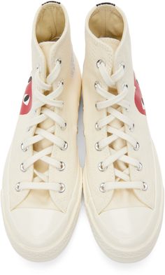 High-top canvas sneakers in off-white. Round rubber cap toe. Tonal lace-up closure. Logo graphic printed in red and black at outer side. Logo printed in red and blue at inner side featuring eyelet vents. Webbing trim in black at heel. Tonal rubber midsole featuring logo at heel. Treaded rubber outsole in brown. Silver-tone hardware. Part of the Comme des Garçons Play x Converse collaboration. Supplier color: Beige Converse Collaboration, Off White Converse, Unique Formal Dresses, Half Heart, Shoe Websites, Fashion Jackson, White Converse, High Sneakers, Comme Des Garcons Play