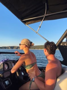 a man and woman sitting in the back of a boat on a body of water