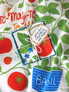 there is a cloth with tomatoes on it and a tag attached to the fabric that says basil