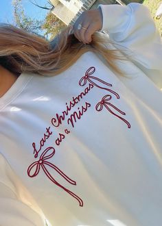 the cutest pullover from six stories! its so buttery soft and has the cutest burgundy embroidered bows and text that reads “last christmas as a miss”. my step mom in law bought my fiance and i matching pullowers that say “hubby” and “wifey” on them from six stories and they are the perfect sweats to cozy up in! my sweet mom ordered this one for me❤️✨🎄christmas sweater. christmas jumper. christmas gift for bride. bride gift. future bride gift. 2025 bride. august 2025 bride. summer 2025 bride. spring 2025 bride. bow sweater. bow clothing. embroidery. embroidered clothing. white jumper. holiday sweater. Bow Clothing, Sweater Bow, 2025 Bride, Embroidered Bows, Christmas Bride, Clothing Embroidery, Mom In Law, Patagonia Pullover, Step Mom