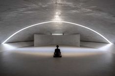 a person sitting in the middle of a room with white walls and lights on it